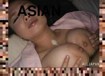 A guy plays with his Asian wife's big tits while she sleeps