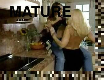 Mature blonde plays lesbian games with a cute teen in the kitchen