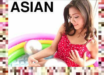 Asian in an inflatable pool pumping a plug into her pussy