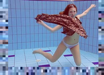 Slim redhead looker dives around the pool in the nude