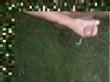 Uncut cock ejaculating a huge load onto the lush green grass in boots and t-shirt
