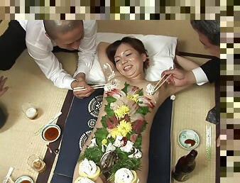 Japanese business men eat food off a beautiful girl