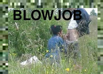 A guy lets a hot chick blow him out in the middle of a field