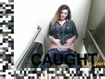 Big boobed babe caught masturbating in a public toilet!