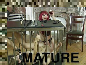 Redhead mature mistress lets her slave out f the cage to abuse her