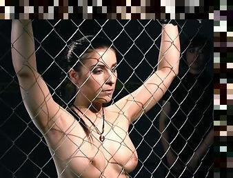 Good looking brunette girl gets tied up to the fence