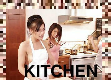 Three awesome brunettes wearing aprons share a wang in the kitchen