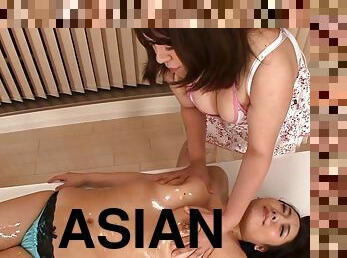 One Asian girl oils up, massages and fingers another