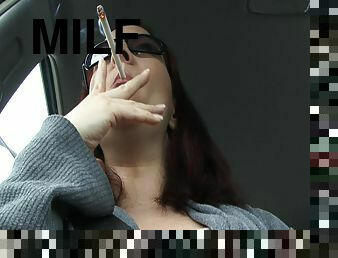 Sexy woman smokes while being in car