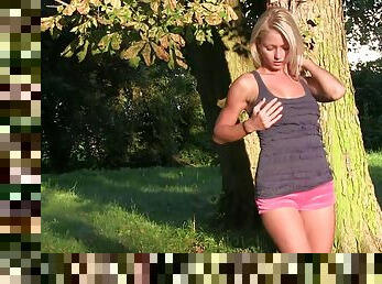 Lovely blonde Pinky June, wearing shorts, fingers her pussy outdoors