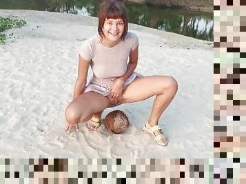 A shy girl squirts a small trickle of pee on a coconut