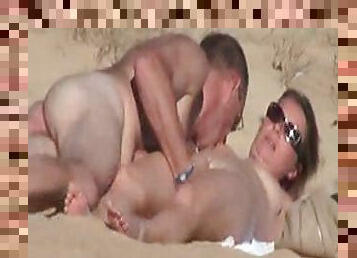 Naked couple doing hand work on the sand