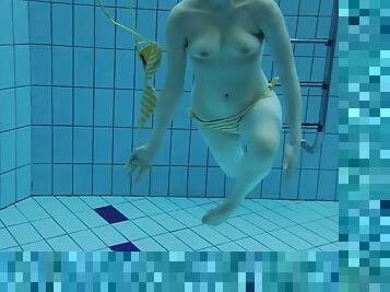 Brunette lady takes off her swimsuit while swimming underwater