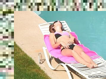 Bikini clad brunette solo model sun bathing by the pool