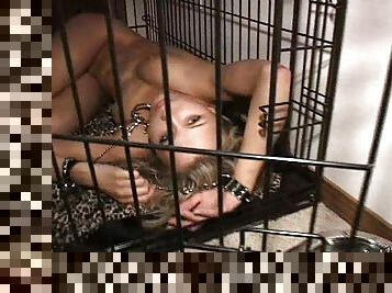 Stocking-clad sex slave with long blonde hair chained up in a cage