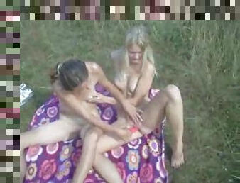 Lesbian couple playing lustily in the grass
